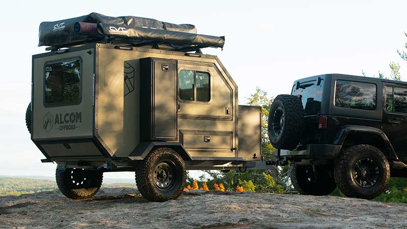 A Oxbow overland camper parked on a rocky outcropping with a Jeep.