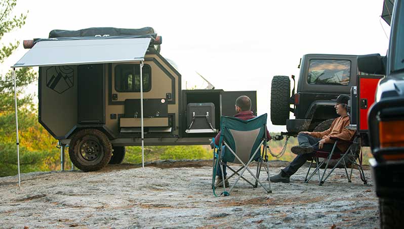An ALCOM Offroad overland camper with a ladder to access the fully setup rooftop tent.