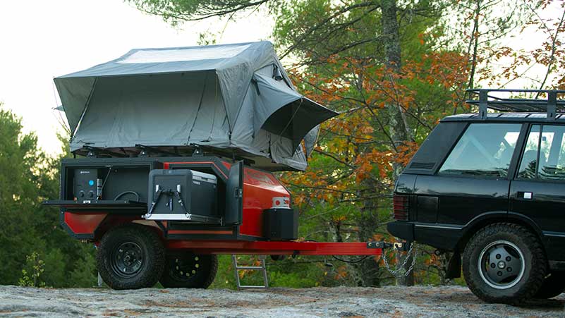 An ALCOM Offroad overland camper with rooftop tent, Dometic refrigerator, and propane tank fully setup for a night of camping.