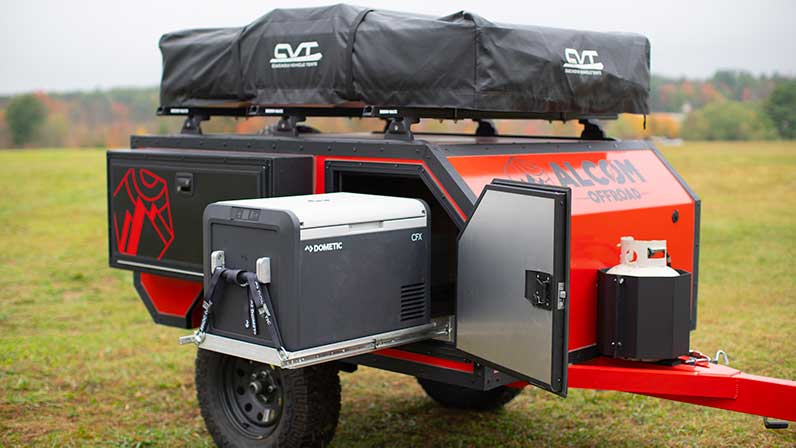 A Spur overland camper with a slide out Dometic fridge/freezer combo on display in a field.